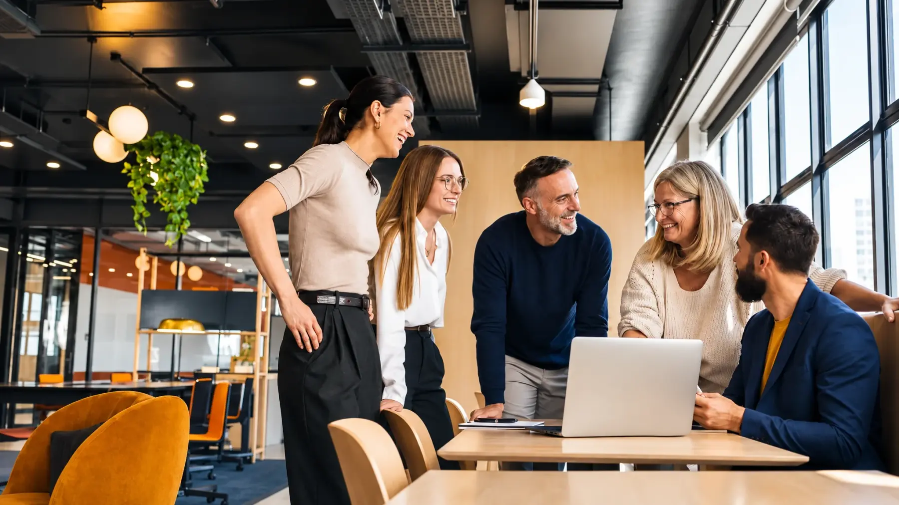 Fünf Personen besprechen ein Projekt am Laptop in einem hellen Büro